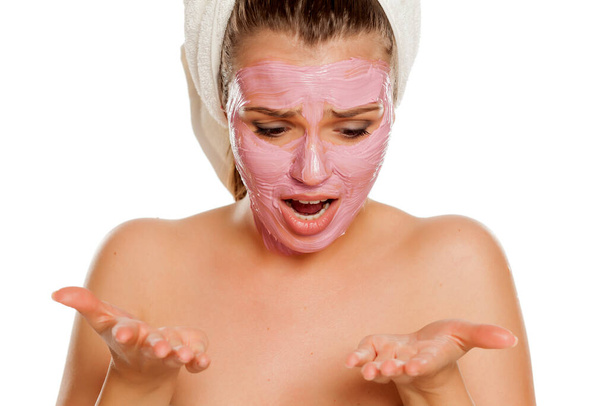 młoda nerwowa i nieszczęśliwa kobieta pozująca z maską na twarzy z ręcznikiem na głowie - Zdjęcie, obraz