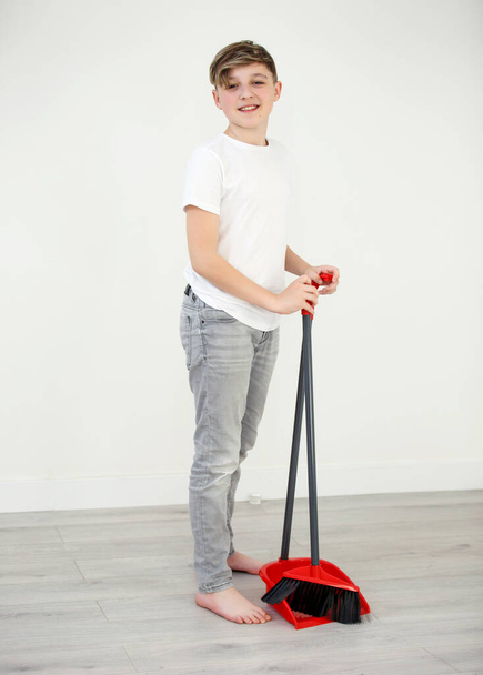 Egy seprűs fiú takarít a szobában. Takarítási koncepció. Kereső kamera. - Fotó, kép