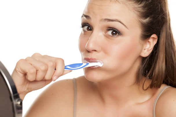 junge glückliche Frau beim Zähneputzen auf weißem Hintergrund - Foto, Bild