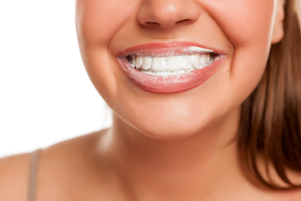 молода усміхнена жінка з піною зубної щітки на зубах на білому тлі
 - Фото, зображення