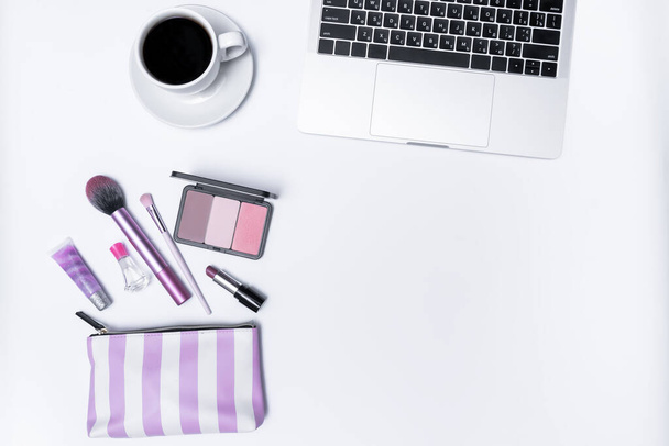 Frauenarbeitsplatz, Laptop, Tasse Kaffee und Kosmetik auf weißem Hintergrund. Ansicht von oben - Foto, Bild