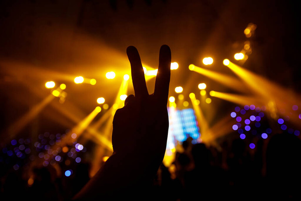 Silueta negra de la mano sobre el fondo de la escena del concierto. Dos dedos.
 - Foto, imagen