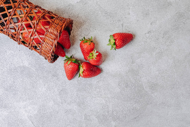juicy strawberries poured out chaotically on a concrete light background. delicious fruits in summer season. natural products and natural resources. simple picture. - Photo, image