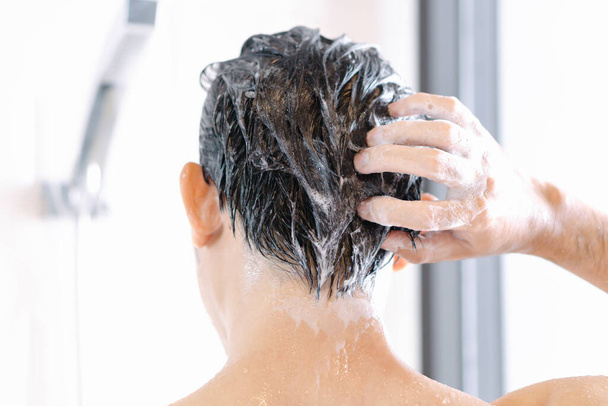 Vértes fiatalember mosás haját a samponnal a fürdőszobában, Vintage Tone, szelektív fókusz - Fotó, kép