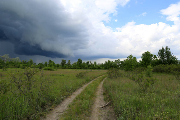 Landschap met onverharde weg in steppe voor onweer, neem het in Oekraïne - Foto, afbeelding