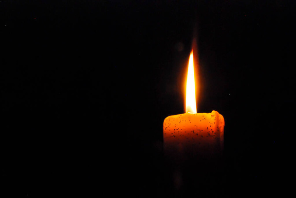 Eine Kerze brennt hell im schwarzen Hintergrund - Foto, Bild