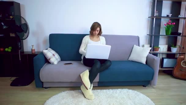 Girl working on a laptop while sitting on a sofa. - Filmmaterial, Video