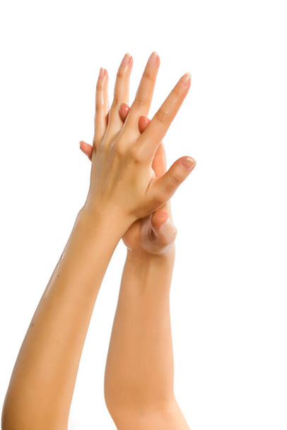 白い背景にハンドクリームを塗る女性の手のクローズアップ - 写真・画像