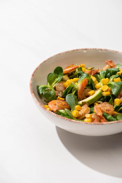 fresh green salad with corn, shrimps and avocado on plate on white background - Photo, Image