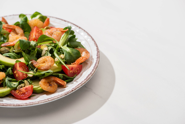 fresh green salad with shrimps and avocado on plate on white background - Valokuva, kuva