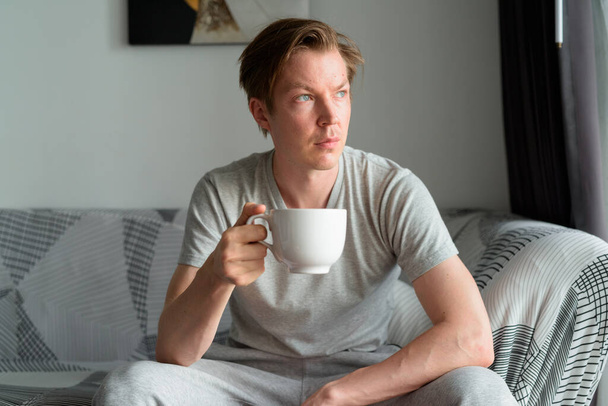 Portrait of young handsome Scandinavian man relaxing in the living room and staying at home - Foto, Imagen