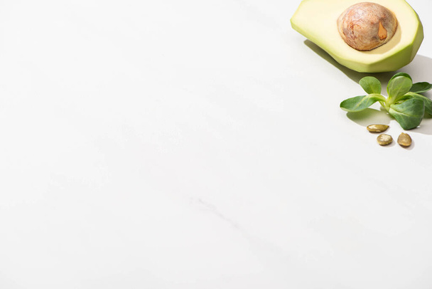 зеленый авокадо, зеленые листья и семена тыквы на белом фоне
 - Фото, изображение