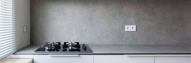 Stylish kitchen with gray countertop and gray wall behind simple kitchen hob - Фото, зображення