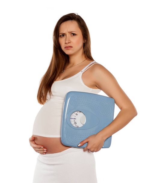 unhappy pregnant woman holding the scales on a white background - Photo, Image