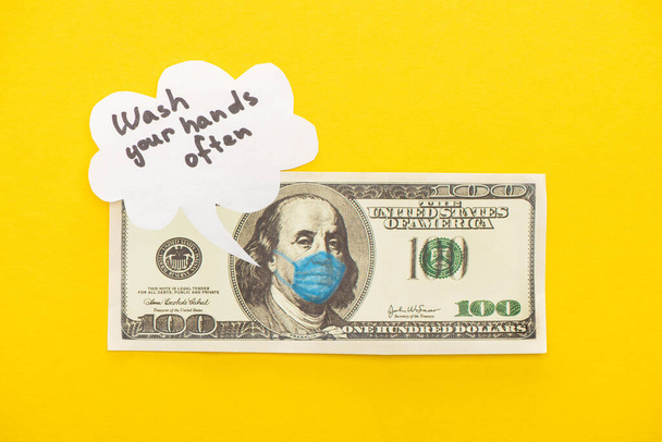黄色い背景に医療マスクと音声バブルが描かれたドル紙幣のトップビュー ロイヤリティフリー写真 画像素材