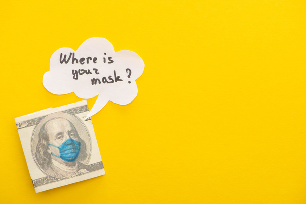 top view of dollar banknote with drawn medical mask and speech bubble on yellow background - Foto, Imagem