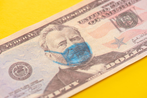 close up view of dollar banknote with drawn medical mask on yellow background - Foto, immagini