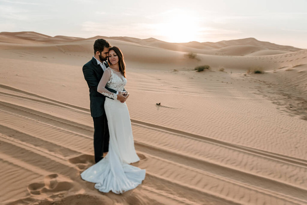 Пара в свадебных платьях в пустыне веселятся, позируя в пустыне. Концепция свадьбы
 - Фото, изображение