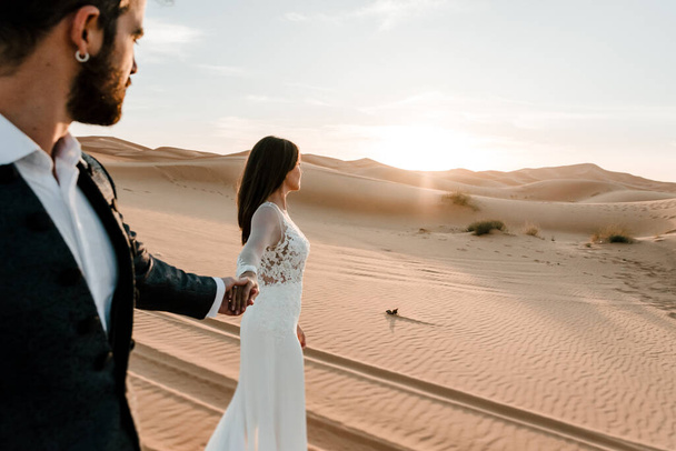 Un couple en robe de mariée dans le désert s'amuse en posant dans le désert. Concept de mariage
 - Photo, image