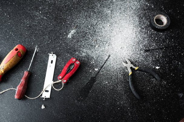 Um conjunto de ferramentas para a auto-instalação da lâmpada encontra-se em uma mesa preta, polvilhada com poeira branca. Marido durante uma hora. Trabalhos domésticos
 - Foto, Imagem