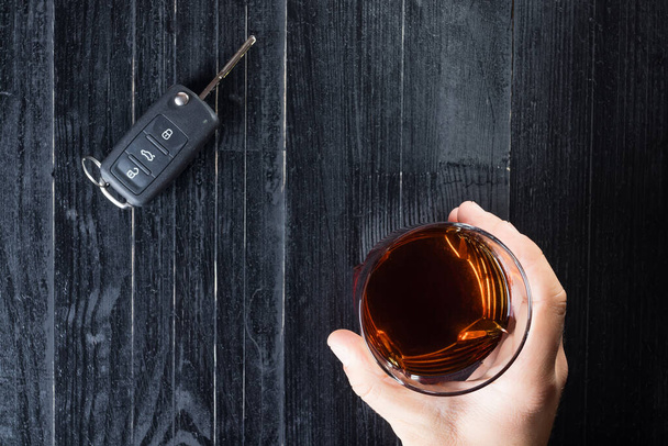 A chave do carro e o álcool de uísque bebem em um copo na mesa de madeira preta. Não beba e conduza o conceito abstrato
. - Foto, Imagem