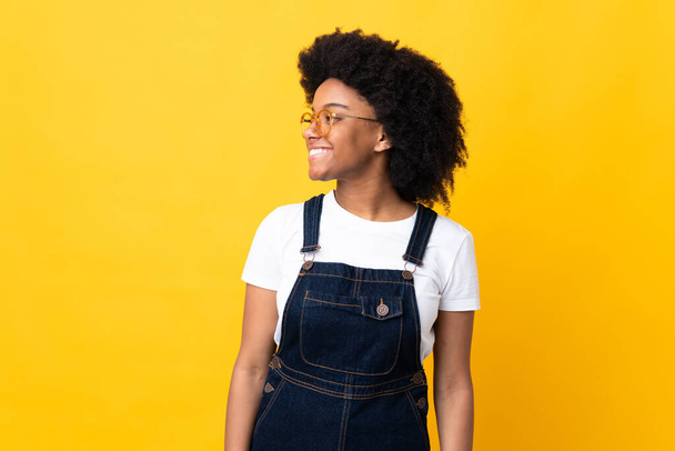Young African American woman isolated on yellow background looking side - Фото, зображення