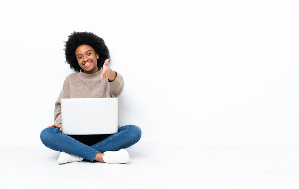 Dizüstü bilgisayarı olan genç Afrikalı Amerikalı kadın iyi bir anlaşma için el sıkışıyor. - Fotoğraf, Görsel