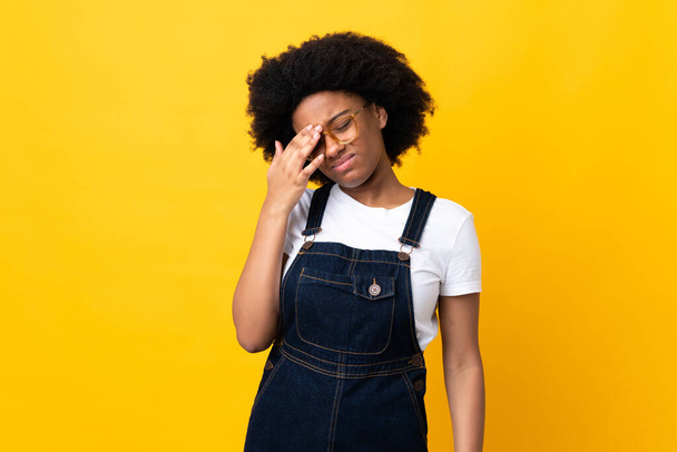 Mujer joven afroamericana aislada sobre fondo amarillo con dolor de cabeza - Foto, Imagen
