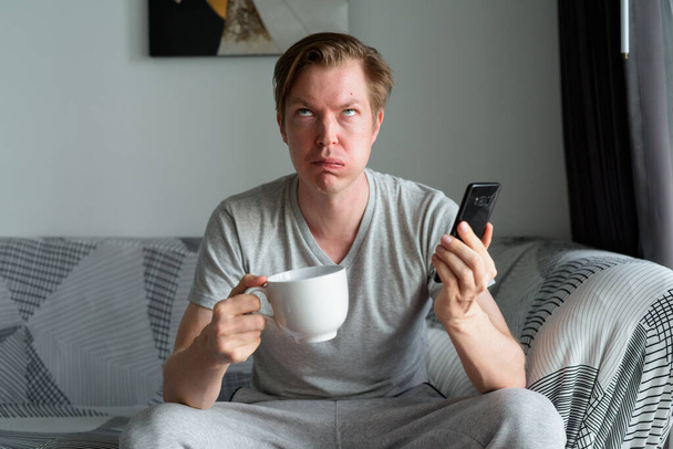 Portrait of young handsome Scandinavian man relaxing in the living room and staying at home - Fotoğraf, Görsel