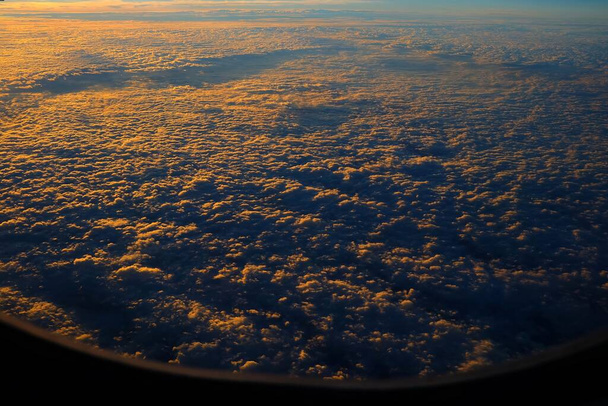 Top View van Wolken met zonsopgang vanuit vliegtuigvenster. - Foto, afbeelding