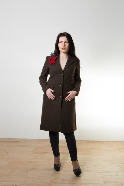 Girl in dark trousers and a brown coat with a brooch - Fotoğraf, Görsel