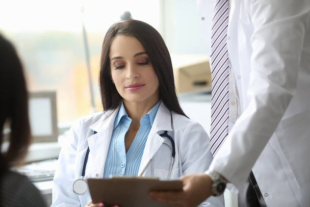 Attentive brunette doctor checking documents during conference - Foto, imagen