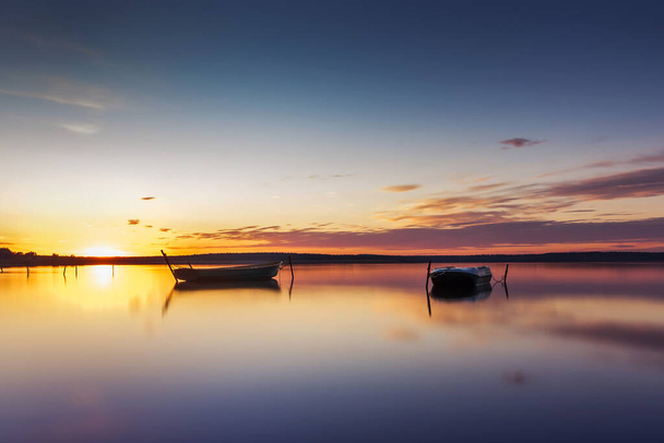 Parking for small fishing boats on the lake during sunset. Long exposure photo - Foto, Imagem