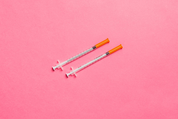 Vue du dessus de deux seringues à insuline à fond coloré avec espace de copie. Concept de haut niveau de glucose. - Photo, image