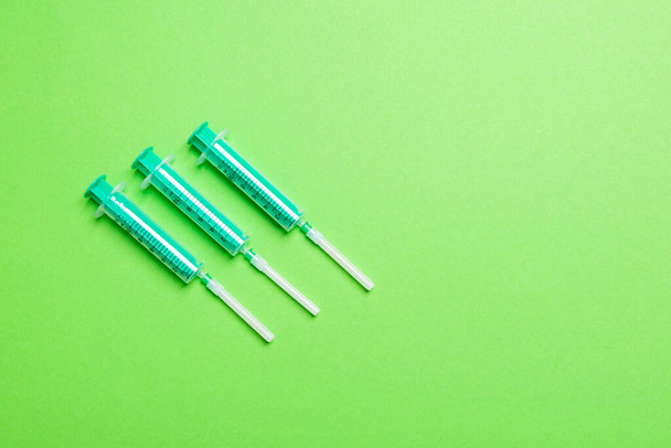 Horní pohled na injekční stříkačky v řadě pro lékařskou injekci na barevném pozadí s kopírovacím prostorem. Zdravotní a vakcinační koncepce. - Fotografie, Obrázek