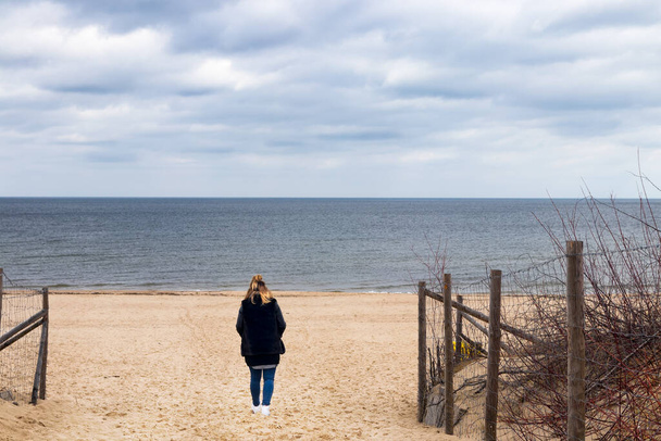 Молодая женщина на пляже смотрит на море с драматическим небом
. - Фото, изображение