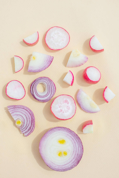 Red sliced onions and radishes on a light pastel background. The concept of healthy vegetables. Textural food background. - Photo, Image