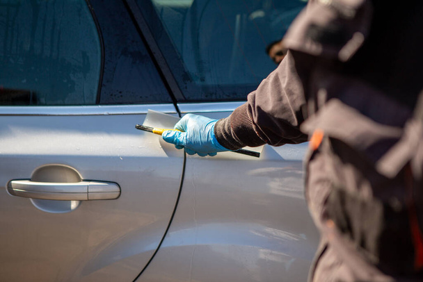 Un operaio in un autolavaggio pulisce l'auto e i finestrini. L'operaio indossa scarpe da ginnastica di gomma blu. Autolavaggio. Copia spazio. - Foto, immagini