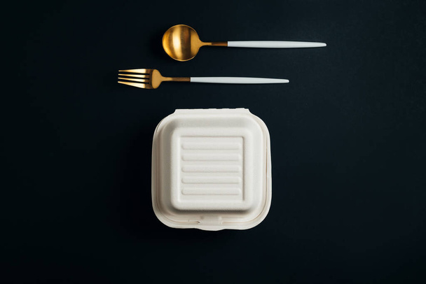 Healthy food concept: white burguer packaging closed with golden fork and spoon - Фото, изображение