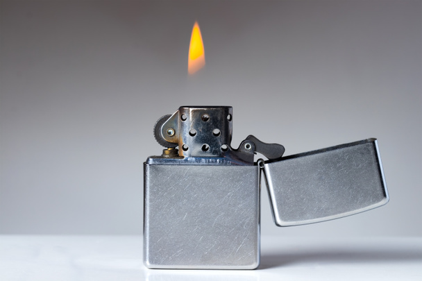 Cigarette lighter with flame on white and grey background. Nicotine and tobacco addiction abstract concept. Copy space on the left. - Valokuva, kuva