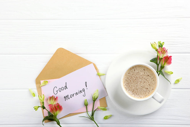 Ένα φλιτζάνι καφέ, ένα μπουκέτο λουλούδια και μια κάρτα με τις λέξεις "καλημέρα". πλατύφυλλο - Φωτογραφία, εικόνα