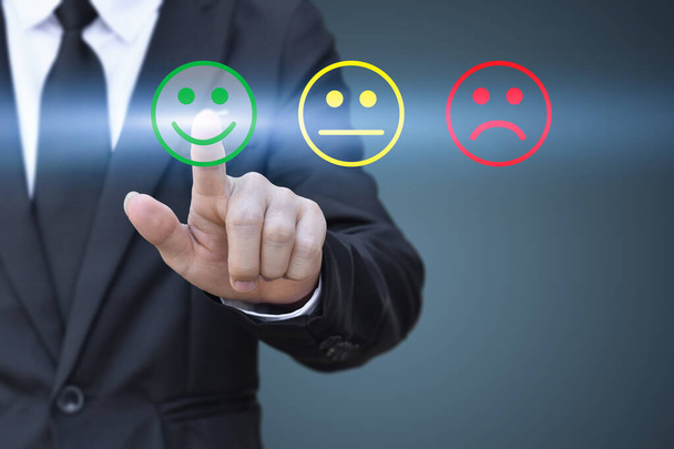 Homme d'affaires appuyant sur l'icône du visage souriant sur l'écran virtuel. Concept d'évaluation de la satisfaction et de rétroaction
. - Photo, image