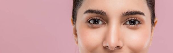 Κοντινό πλάνο πολύ όμορφα μεγάλα μάτια της νεαρής ελκυστικής Καυκάσιας γυναίκας απομονωμένη σε ροζ φόντο. - Φωτογραφία, εικόνα