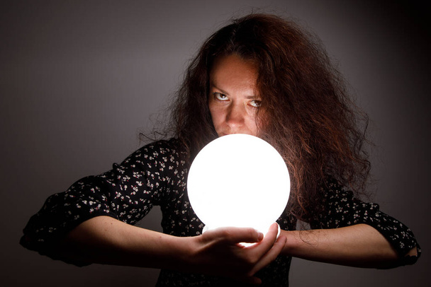 Woman with a luminous ball. Demonic look - Zdjęcie, obraz
