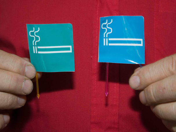 Roken gebied teken, persoon houdt twee stickers in zijn handen - Foto, afbeelding