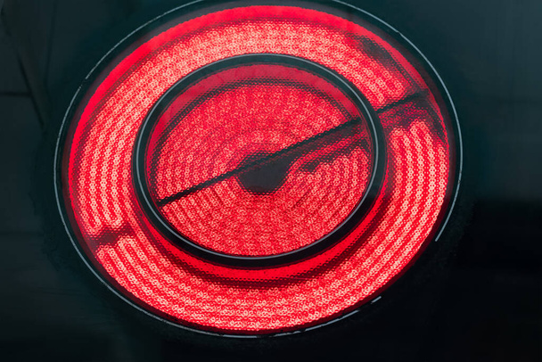 Closeup of modern electric stove burner glowing red. Black background. - Photo, Image