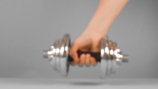 Mão humana com halteres de metal pesado posa em um fundo cinza. Esportes em casa e exercícios
 - Filmagem, Vídeo