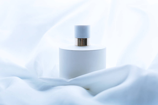 Perfume sobre un fondo de ondas de tela blanca
 - Foto, Imagen