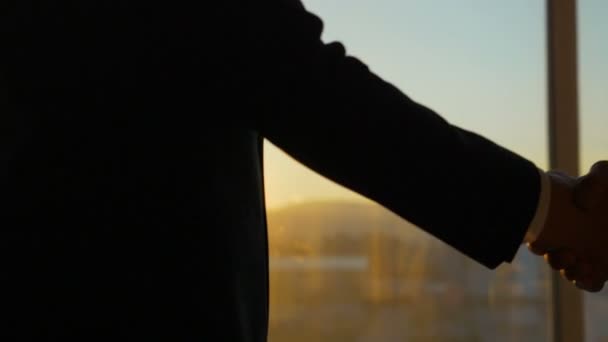 Die beiden Geschäftsleute geben sich vor dem Hintergrund des Sonnenaufgangs die Hand. Zeitlupe - Filmmaterial, Video