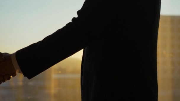 A két férfi kezet rázott a naplemente hátterében. lassított felvétel - Felvétel, videó